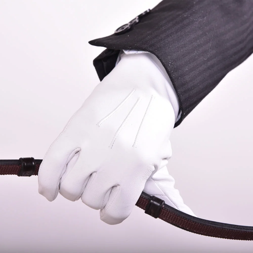A white leather show glove worn on a wrist holding a riding rein, saddle-stitched fourchettes visible on the back of the hand.